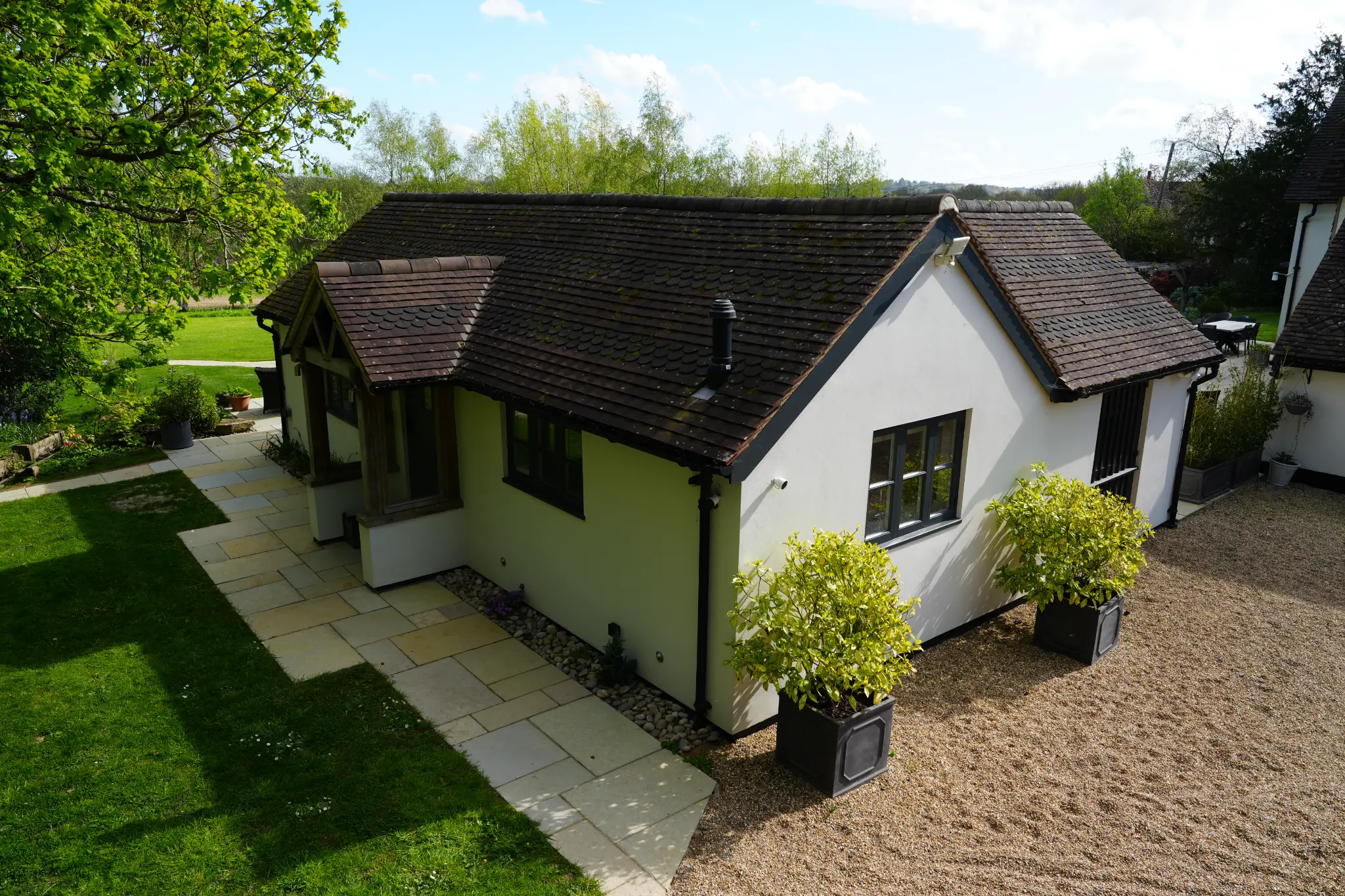 Front elevation of Little Rose with planted pots and driveway.