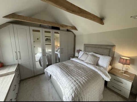 Bedroom at Little Rose with exposed beam and soft neutral styling.